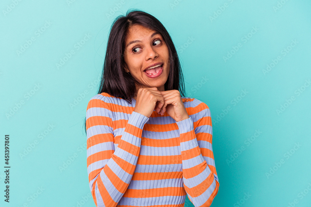 Young latin woman isolated on blue background praying for luck, amazed and opening mouth looking to front. Young latin woman isolated on blue background praying for luck, amazed and opening mouth looking to front.