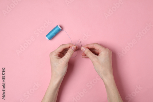 Female hands threading a needle and getting ready to sew