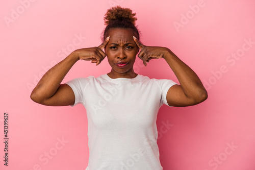 Young african american woman isolated on pink background focused on a task, keeping forefingers pointing head.