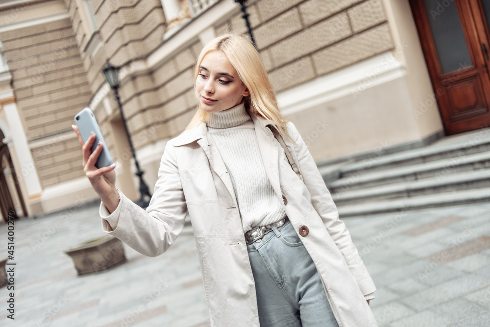 Young stylish blonde woman makes selfie on smartphone in the city Young stylish blonde woman makes selfie on smartphone in the city
