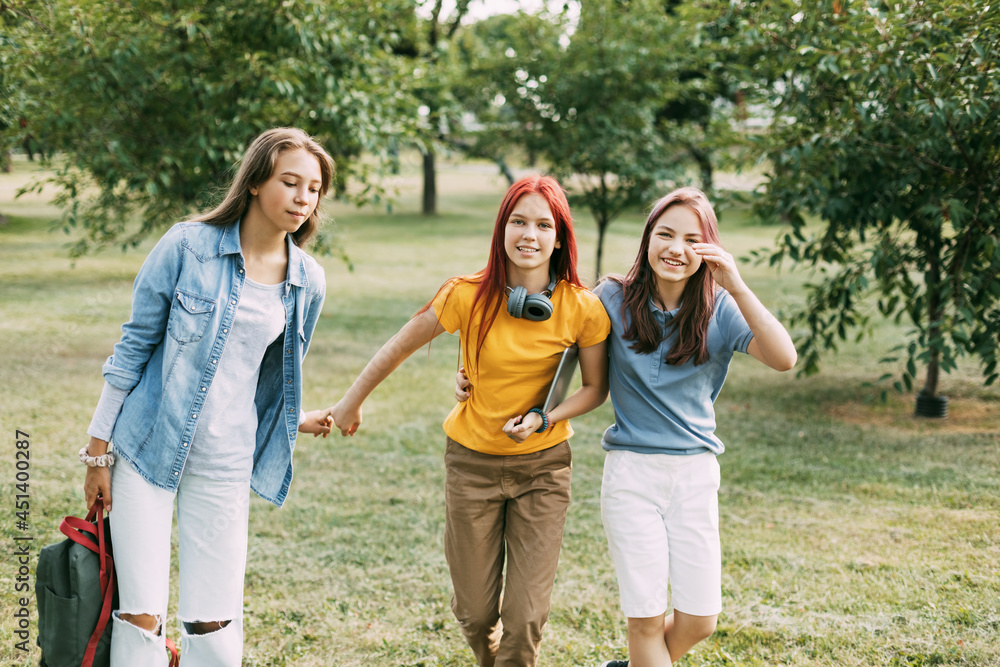 Three teenage girls are walking in the park after school. The concept of training and education. Back to school