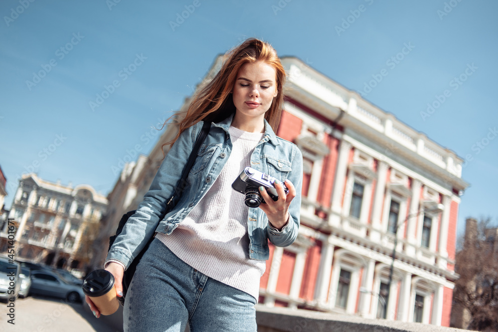 Cute caucasian woman tourist walking with a retro camera in the city