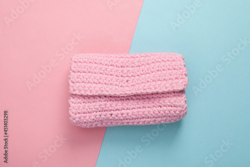 Hand made knitted pink wallet on blue pink pastel background