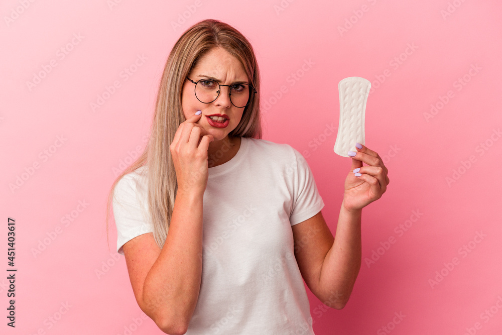 Young russian woman holding a compress isolated on pink background biting fingernails, nervous and very anxious. Young russian woman holding a compress isolated on pink background biting fingernails, nervous and very anxious.