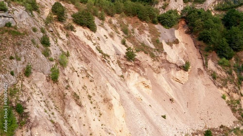 Soil erosion on a steep slope due to landslide. Surface ground movement on unstable hillside. Coastal land deterioration and collapse. Aerial drone view. photo