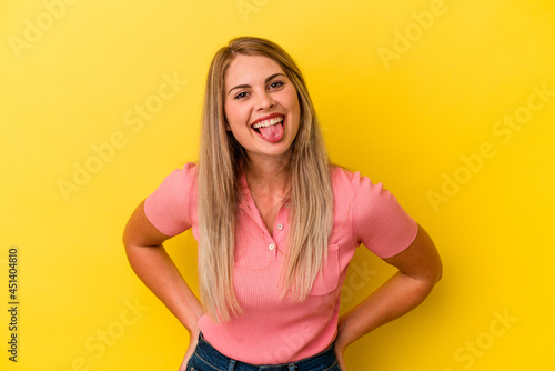 Young russian woman isolated on yellow background funny and friendly sticking out tongue.
