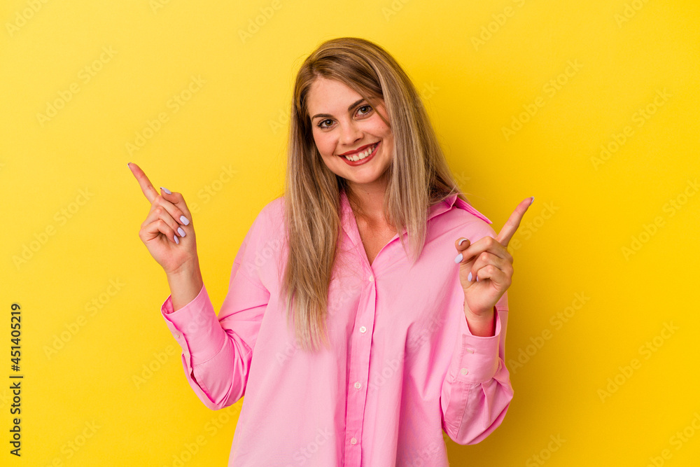 Young russian woman isolated on yellow background pointing to different copy spaces, choosing one of them, showing with finger. Young russian woman isolated on yellow background pointing to different copy spaces, choosing one of them, showing with finger.