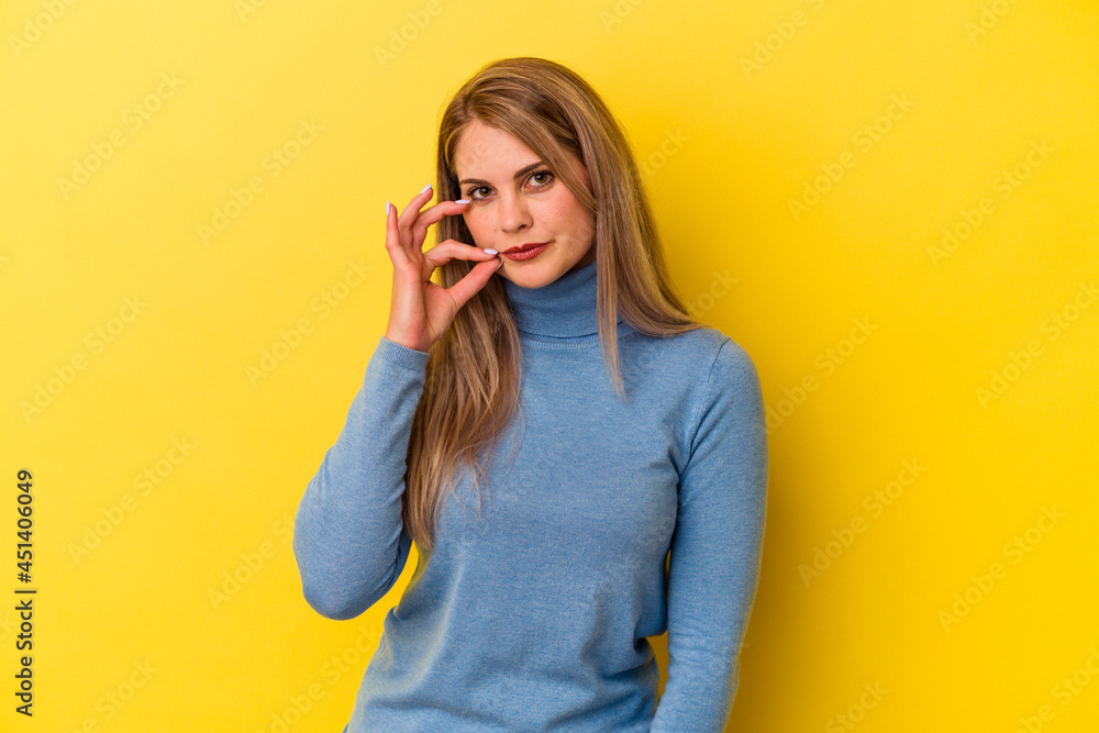 Young russian woman isolated on yellow background with fingers on lips keeping a secret. Young russian woman isolated on yellow background with fingers on lips keeping a secret.