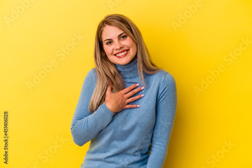 Young russian woman isolated on yellow background laughing keeping hands on heart, concept of happiness.