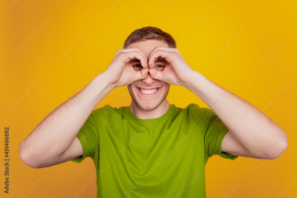 Close up photo of young man show finger okey symbol near eye binoculars fooling isolated yellow bright background Close up photo of young man show finger okey symbol near eye binoculars fooling isolated yellow bright background