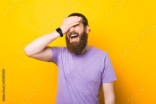 Photos Bearded man is making a face palm in a studio over yellow background
