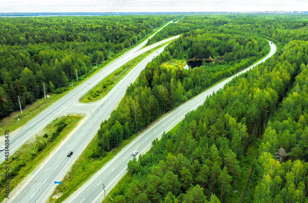 Aerial view of movement of cars on the motorway through the forest