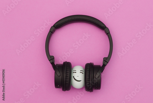 Chicken egg happy face with headphones on pink background.