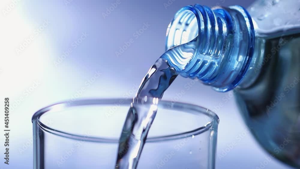 Water Bottle of Transparent Plastic Filling a Drinking Glass on a Blue Background Water Bottle of Transparent Plastic Filling a Drinking Glass on a Blue Background