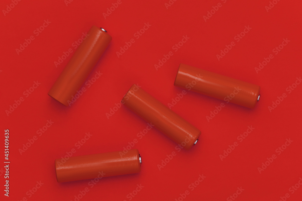 Four AA batteries on red background. Top view Four AA batteries on red background. Top view