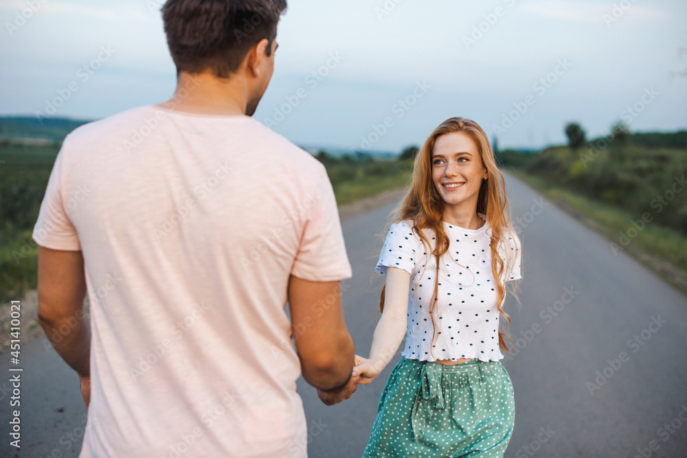 Couple holding hand and walking on road. Beautiful ginger woman with freckles. Love concept Couple holding hand and walking on road. Beautiful ginger woman with freckles. Love concept