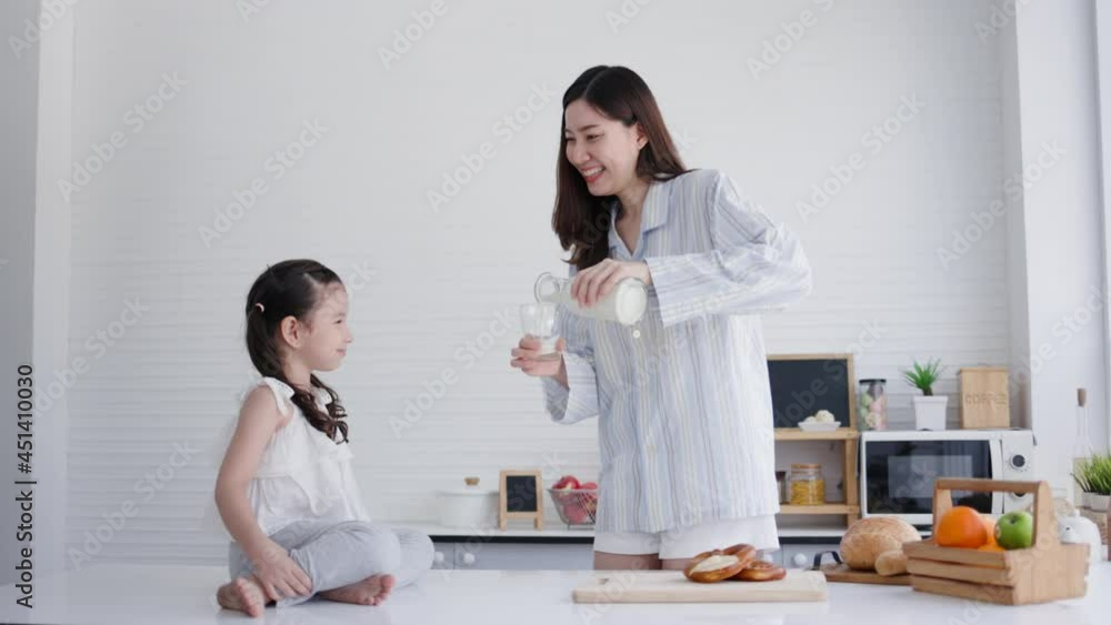 Mother and daughter happy to drink fresh milk in kitchen at home. Milk is beneficial for growth of body for children. family living together with love. Weekend activity happy family lifestyle concept Mother and daughter happy to drink fresh milk in kitchen at home. Milk is beneficial for growth of body for children. family living together with love. Weekend activity happy family lifestyle concept