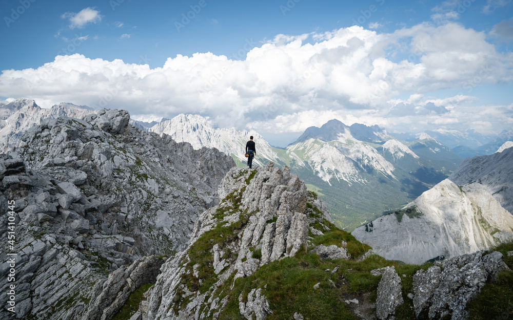 Adventurous man is standing on top of the mountain and enjoying the beautiful view. Taken from mountain Tajakopf near Leermos ehrwald Austria alps