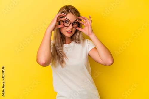 Young russian woman isolated on yellow background keeping eyes opened to find a success opportunity.