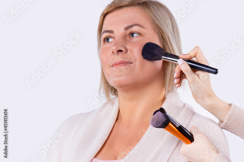 Business pretty blond woman with light complexion gets makeup for preparing for business meeting.