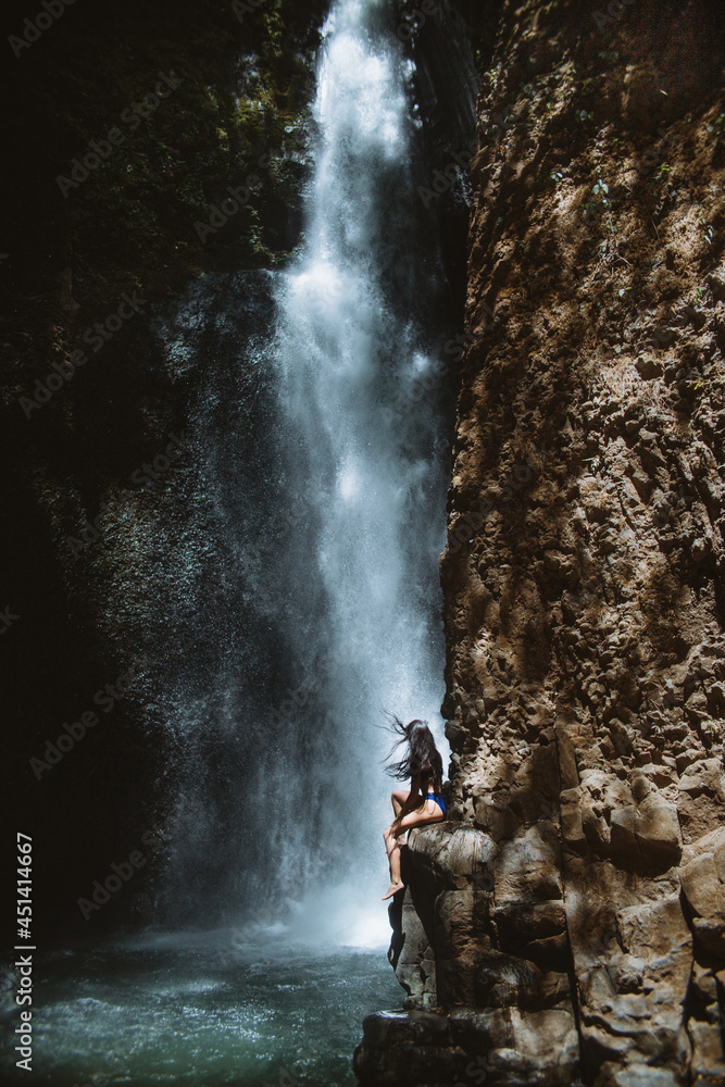 Woman sitting on rock near waterfall Woman sitting on rock near waterfall