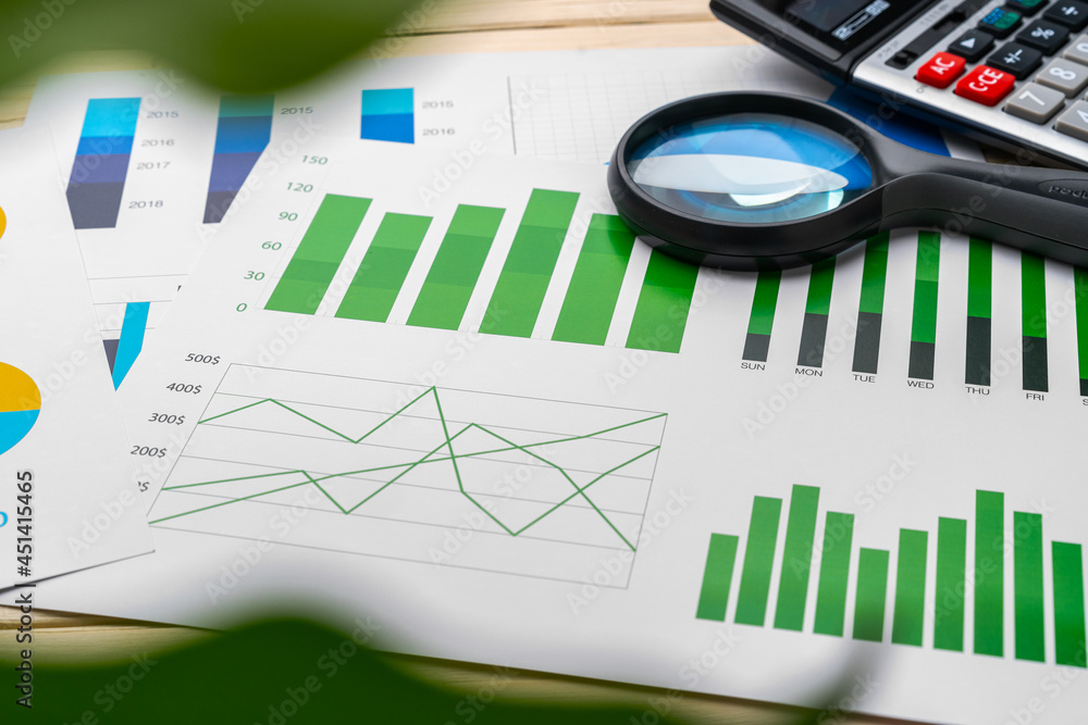 Obraz premium Business graphs and magnifying glass on table