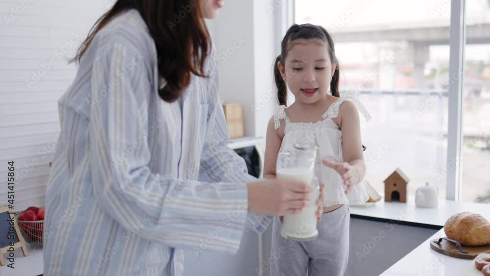 Mother and daughter happy to drink fresh milk in kitchen at home. Milk is beneficial for growth of body for children. family living together with love. Weekend activity happy family lifestyle concept Mother and daughter happy to drink fresh milk in kitchen at home. Milk is beneficial for growth of body for children. family living together with love. Weekend activity happy family lifestyle concept