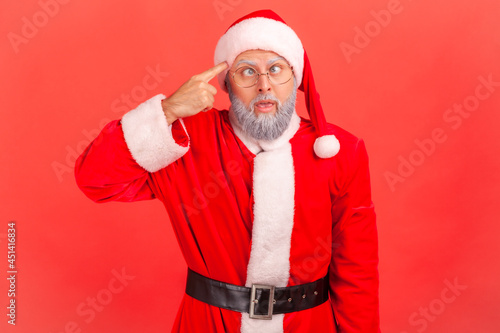 Canvas Print Elderly man with gray beard in santa claus costume crossed eyes, showing stupid gesture, looking at camera with condemnation and blaming for insane plan