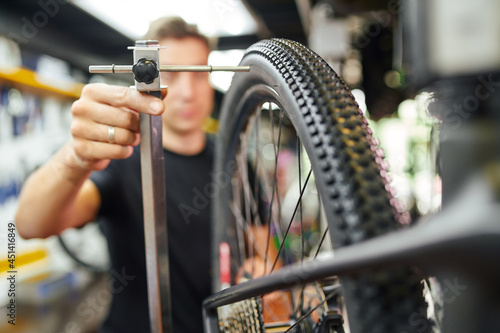 Mechanic centering bike wheel on truing stand photo