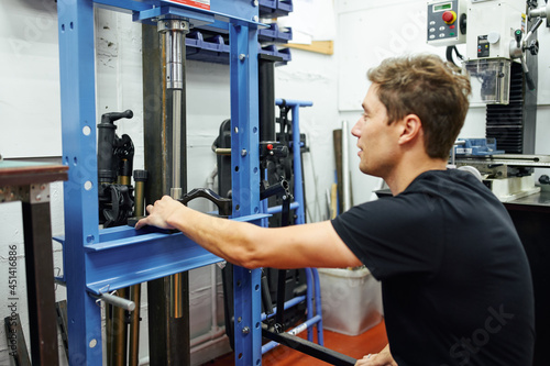 Male mechanic using hydraulic press photo