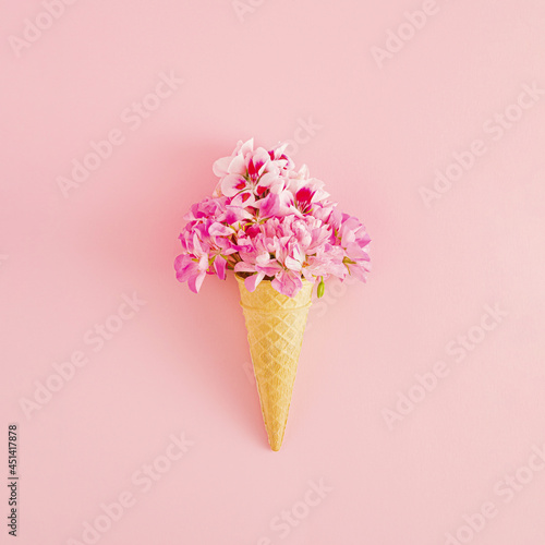 Creative idea of ice cream with .pink flowers in a cone on pink background. Minimal summer or dessert concept. © Anita