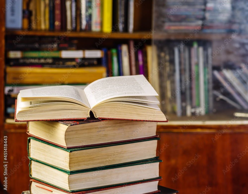 An open book on a stack in front of a bookcase. Learning concept An open book on a stack in front of a bookcase. Learning concept