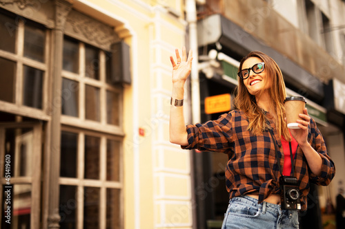 Beautiful young woman drinking coffee. Portrait of happy woman in the city..