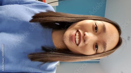 Vertical video of asian young woman has chat with friends with smart phone. Video calling in online chat using smartphone at home.