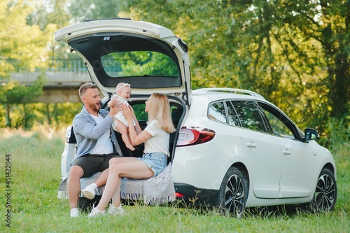 Happy family near car trunk on sunny day. Road trip © Serhii