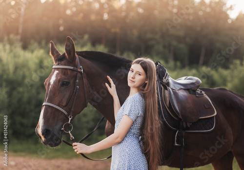 Portrait of young girl standing next to a horse looking at camera smiling.