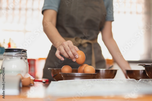 Woman chef pick up fresh raw egg preparing ingredient for making healthy cuisine.