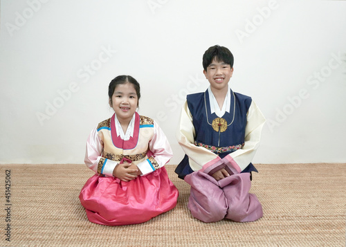 한복을 입고 웃으며 멍석 위에 앉아있는 아이들 Smiling children wearing Hanbok sitting on the mat 