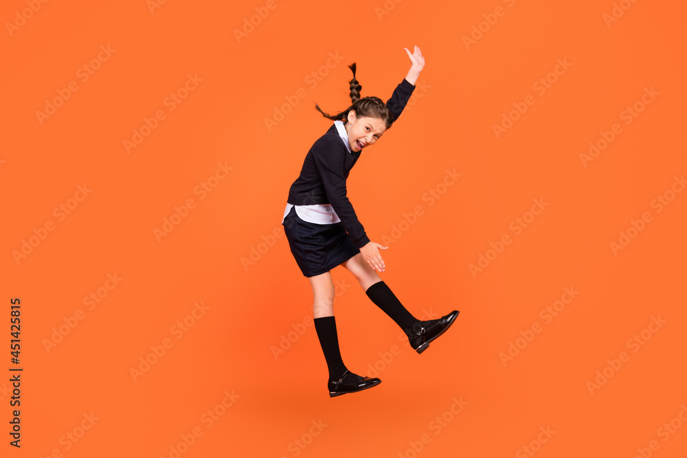 Full length body size view of trendy cheerful comic preteen girl jumping fooling dancing isolated over bright orange color background Full length body size view of trendy cheerful comic preteen girl jumping fooling dancing isolated over bright orange color background