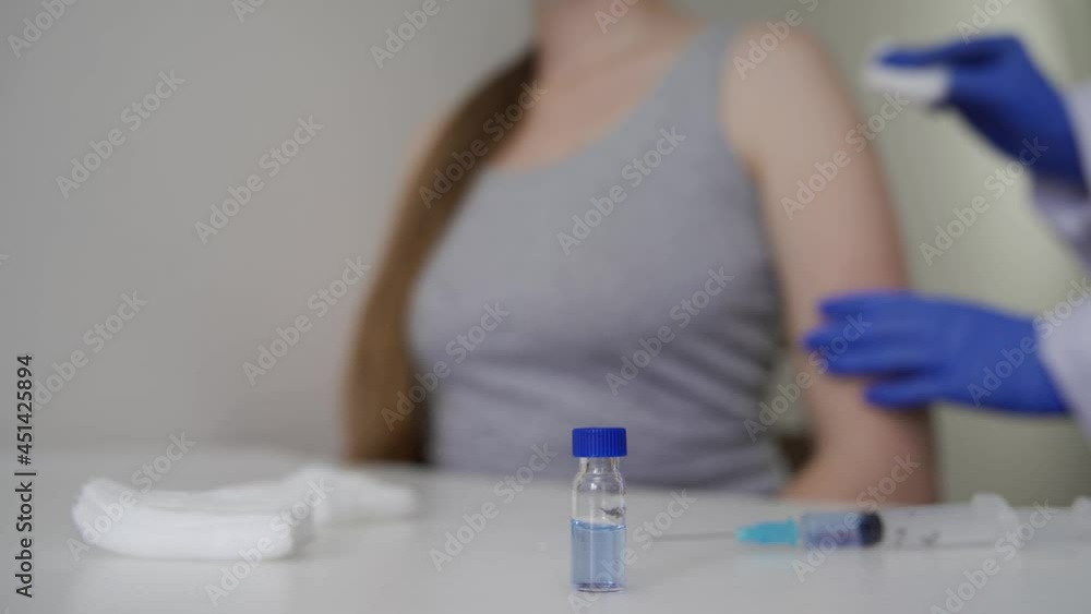 A doctor in rubber blue gloves gives a coronavirus vaccine to a patient. Protection from a dangerous virus. Maintaining health. Close-up, blurred background, 4K UHD. A doctor in rubber blue gloves gives a coronavirus vaccine to a patient. Protection from a dangerous virus. Maintaining health. Close-up, blurred background, 4K UHD.