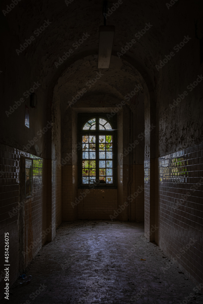 A corridor, with a mosaic window, inside an abandoned asylum