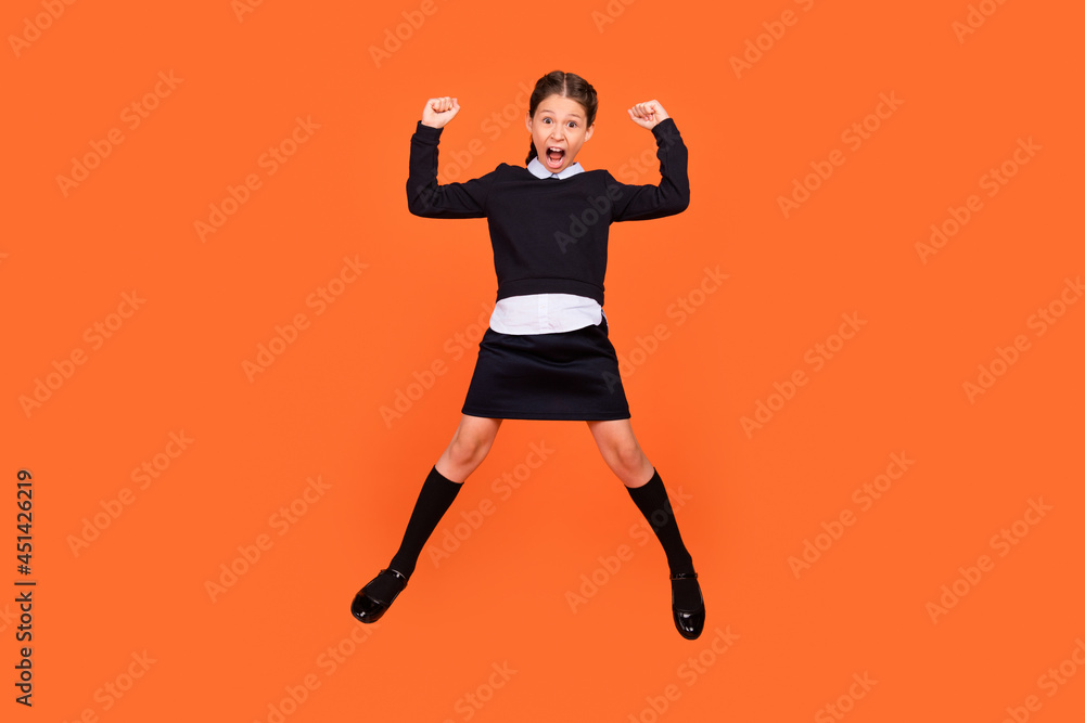 Full length photo of young girl happy positive smile celebrate victory success fists hands jump isolated over orange color background