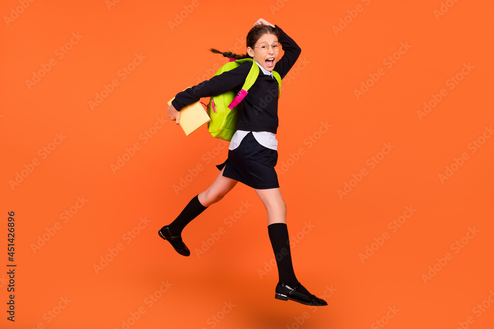Full length body size view of pretty cheerful schoolgirl nerd jumping going to college isolated over bright orange color background
