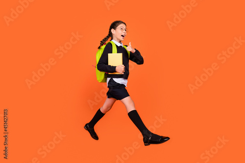 Full body profile side photo of young girl happy smile show thumb-up fine great go jump lesson isolated over orange color background