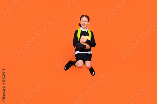 Full body photo of brunette small amazed shocked girl jump up hold hug book isolated on orange color background