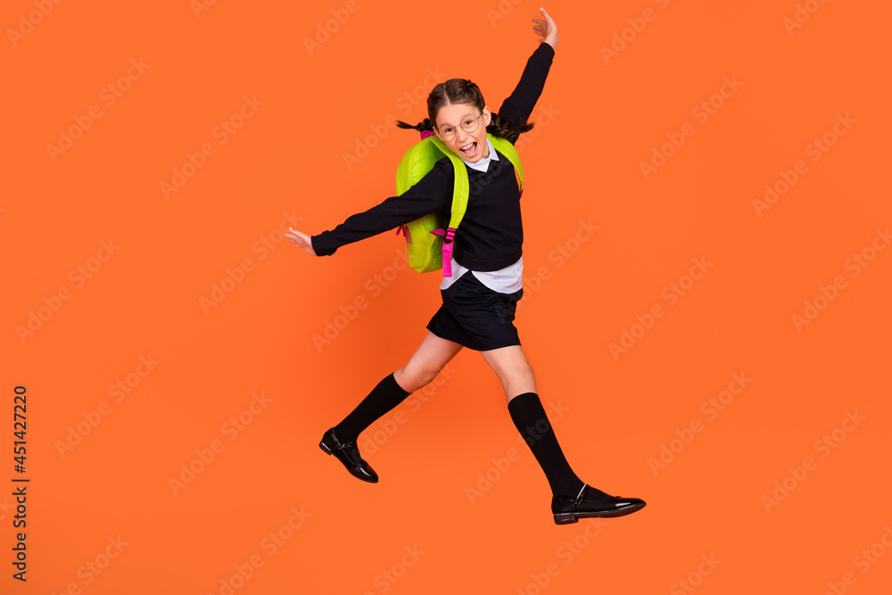Full size photo of cheerful happy positive small girl jump up crazy wear bag isolated on orange color background
