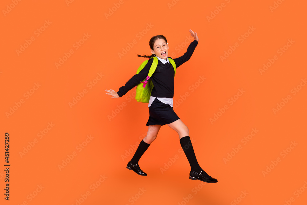 Full length body size view of nice pretty funky cheerful schoolgirl jumping walking isolated over bright orange color background