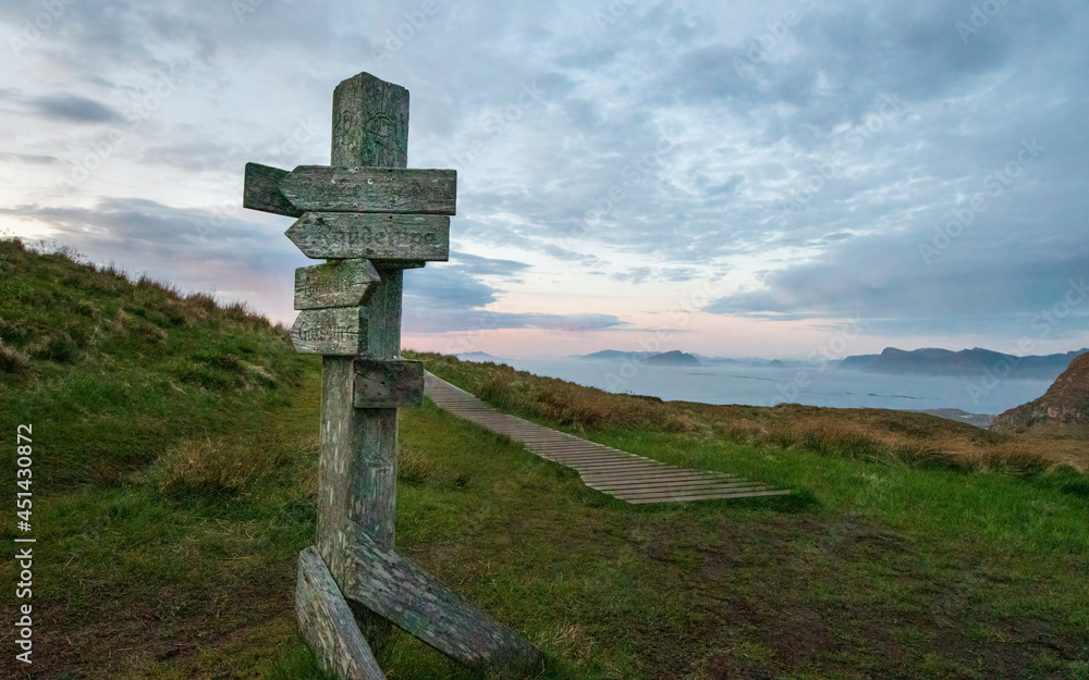 Old wooden sign with a wood trail on Norwegian mountain in sunset with copy space Old wooden sign with a wood trail on Norwegian mountain in sunset with copy space