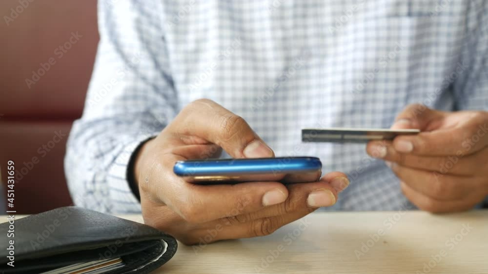 young man putting credit card detail on smart phone young man putting credit card detail on smart phone