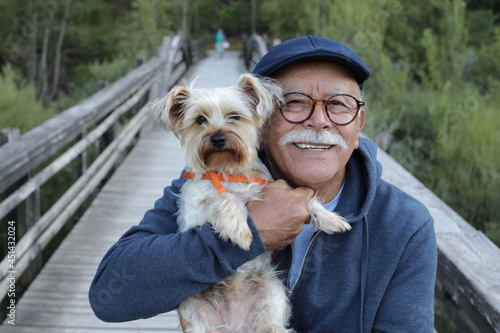 Ethnic senior man with small dog in the park photo